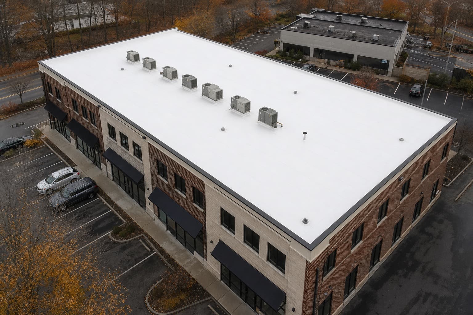 Aerial view of a completed white TPO flat roof on a New England retail plaza