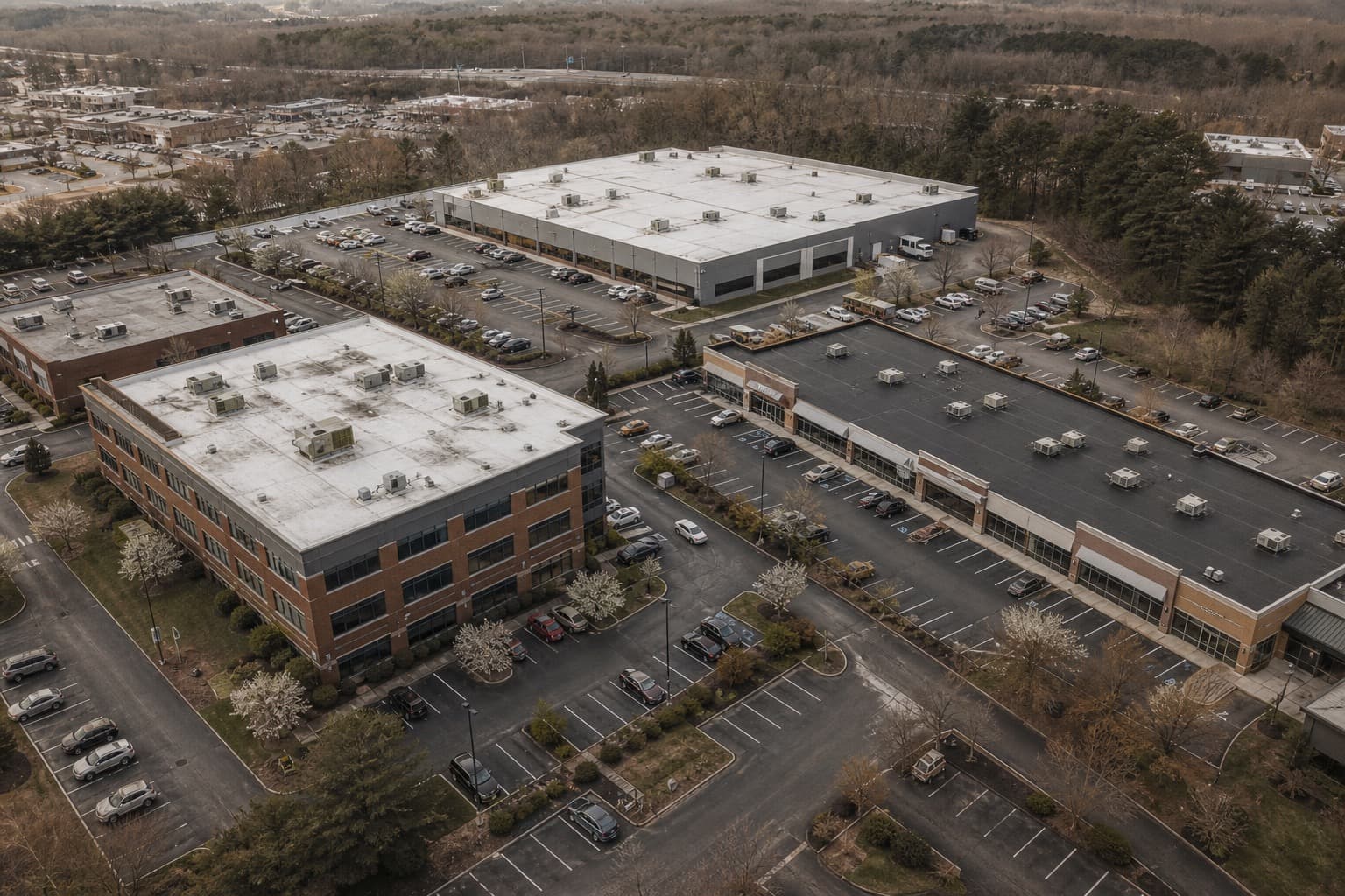 Aerial view of several mid-size commercial buildings with flat roofs in one managed portfolio
