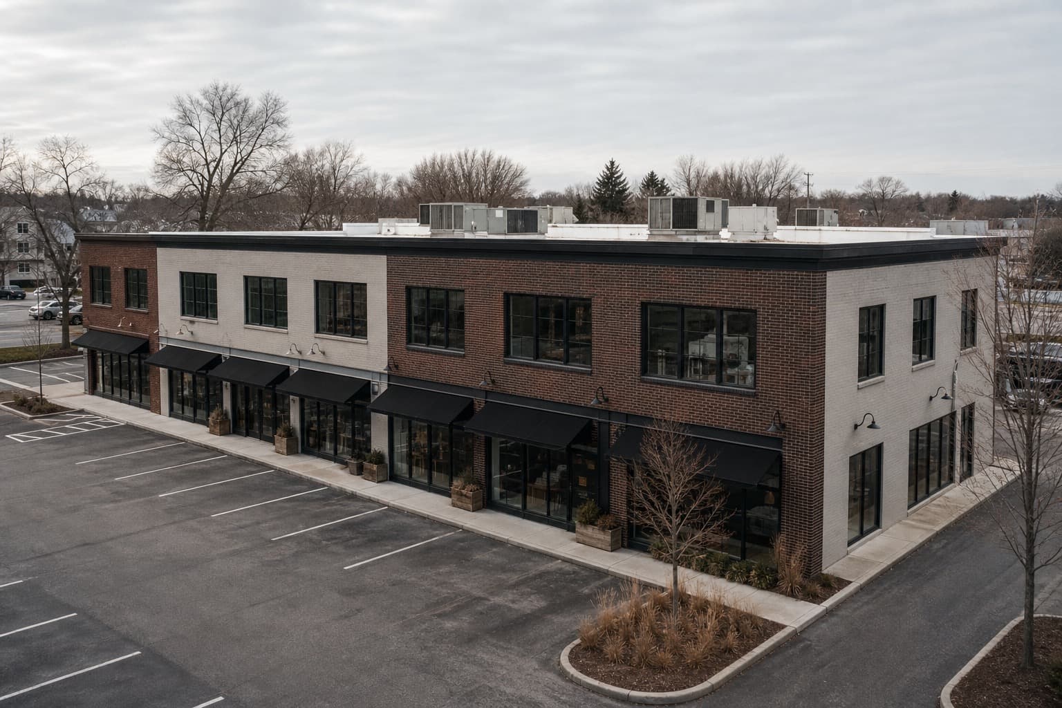 Flat white TPO roof over a mid-size New England multi-tenant retail plaza